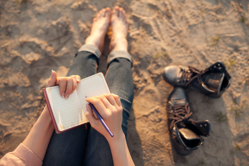 Inner Growth women writing in diary on sand